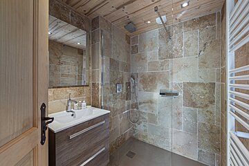 A bathroom with a walk in shower and a sink