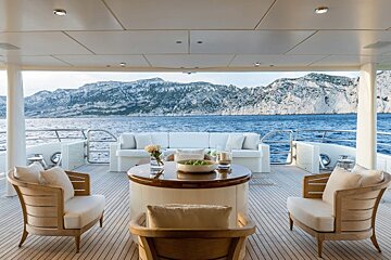 A couch and chairs on a boat with mountains in the background