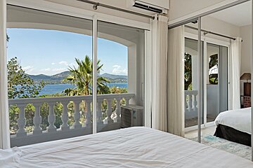A bedroom with a view of the ocean and mountains