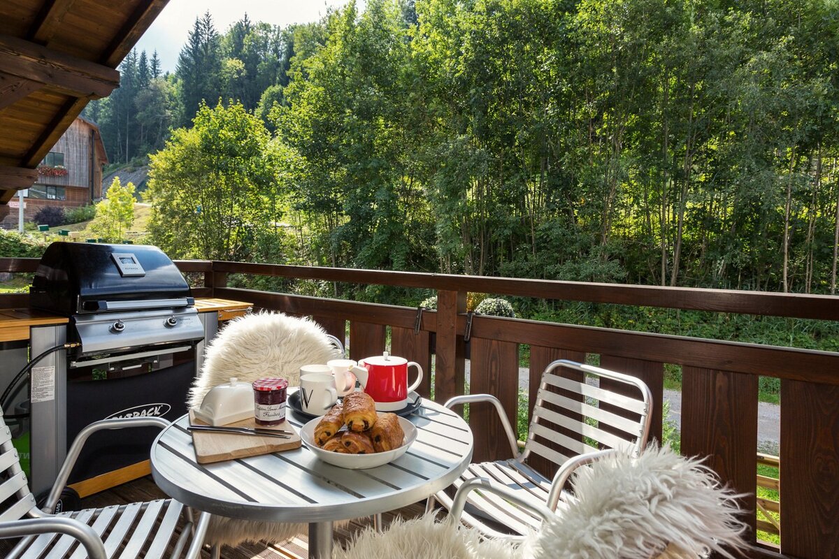 A table with a bowl of croissants and a jar of jam on it