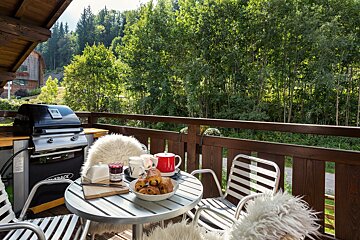 A table with a bowl of croissants and a jar of jam on it