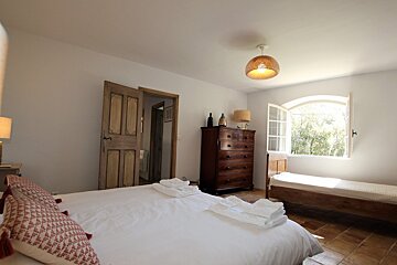 A bedroom with a bed a dresser and a window