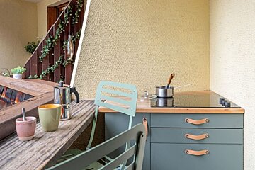 A kitchen with a pot on the stove and cups on the counter