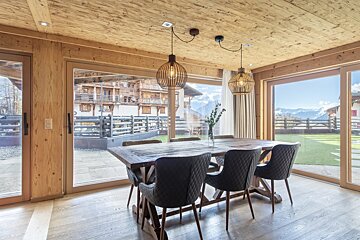 A dining room with a table and chairs and a view of the mountains