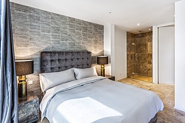 A bedroom with a large bed and a walk in shower