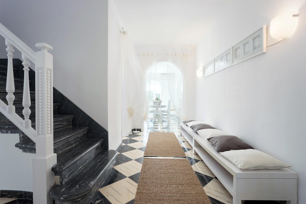 A hallway with stairs and a bench with pillows on it