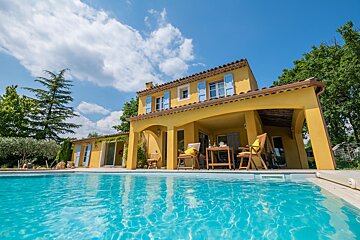 A yellow house with a swimming pool in front of it