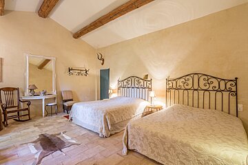 A bedroom with two beds and a rocking chair
