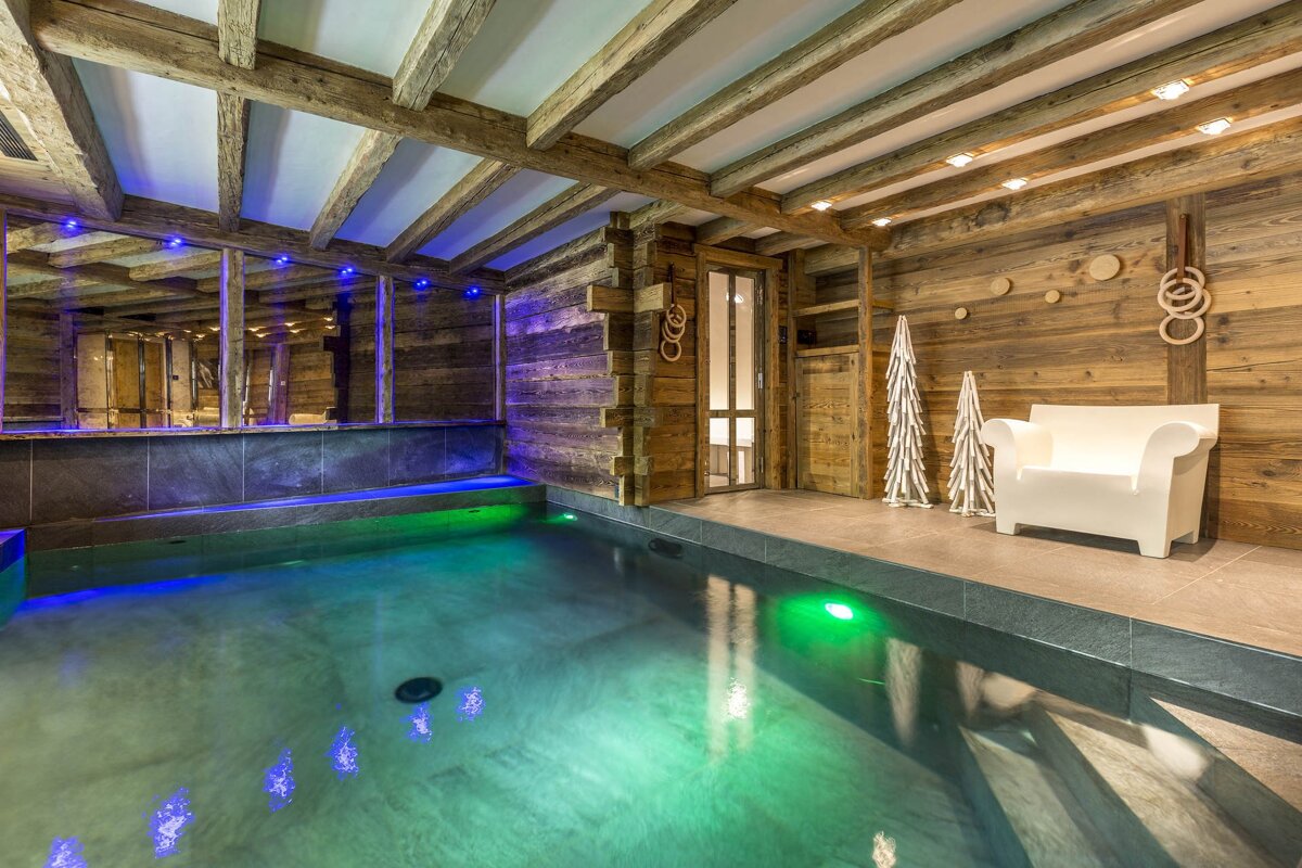 A swimming pool in a room with a chair and christmas trees