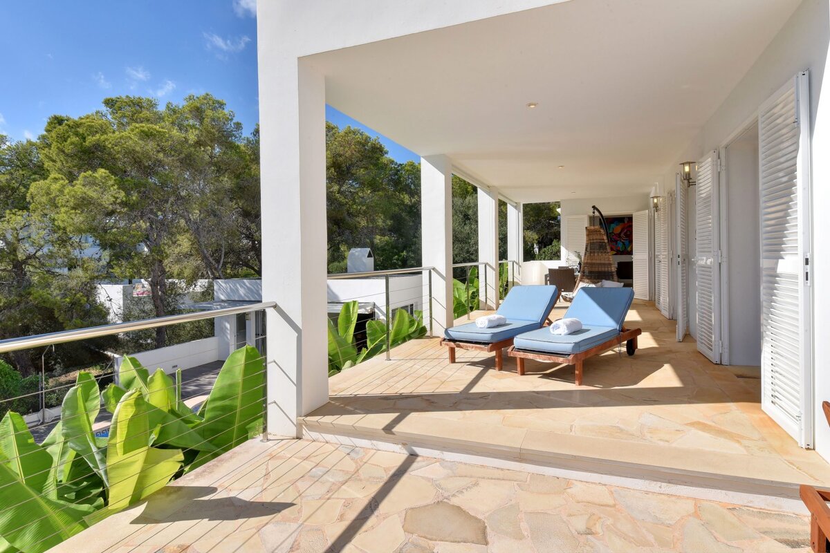 A balcony with two blue lounge chairs on it