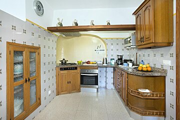 A kitchen with wooden cabinets and a clock on the wall