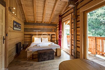A bedroom in a log cabin with a bed and a large window