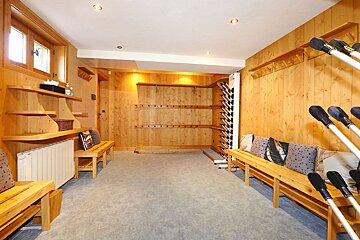 A room with wood paneling and a bench with skis on it