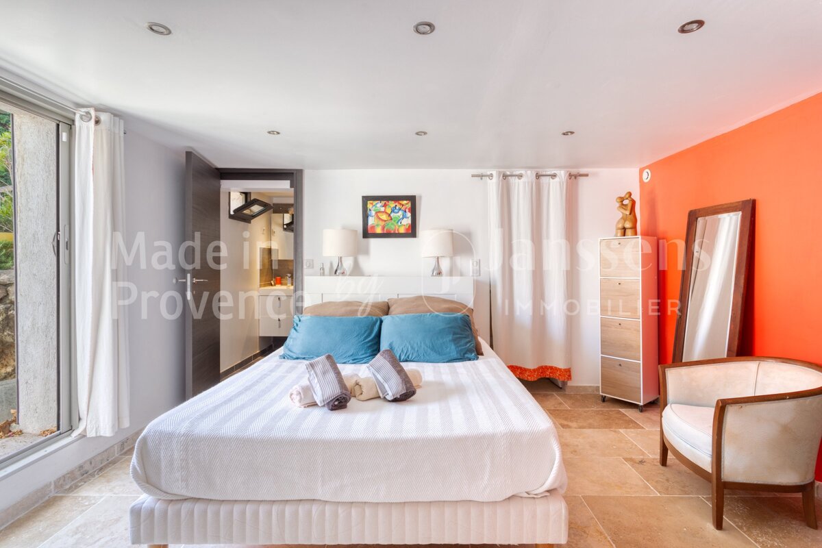 A bedroom with a bed and a chair and the words made in provence on the wall