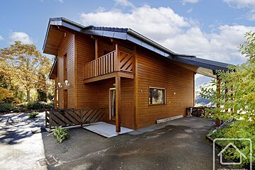 A wooden house with a balcony and a sign that says atelier property