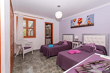 A bedroom with two beds and a painting of flowers on the wall
