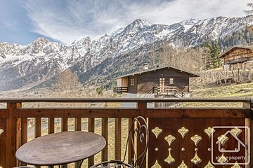 A balcony with a table and chairs overlooking a snowy mountain range