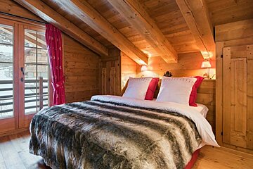 A bed with a fur blanket and pillows in a wooden room