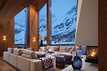 A living room with a fireplace and a view of snowy mountains