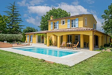 A yellow house with blue shutters sits next to a large swimming pool