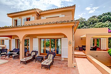 A large house has a patio area with chairs and tables