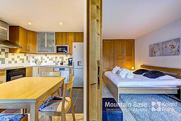 A bedroom with a bed and a kitchen with a sign that says mountain base knight frank
