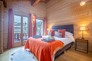 A bedroom with a large bed and a balcony