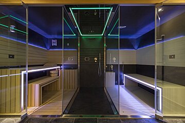 A sauna with green and blue lights on the ceiling