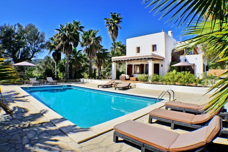 A white house with a large swimming pool in front of it