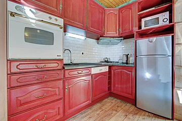 A kitchen with red cabinets and a silver refrigerator