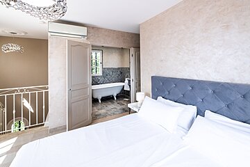 A bedroom with a claw foot tub in the bathroom