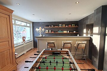 A game room with a foosball table and a bar