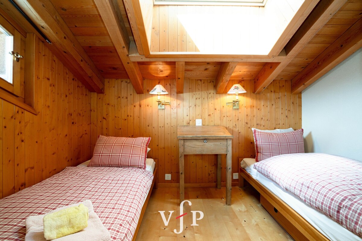 A bedroom with two beds and a table with the letter v on the floor