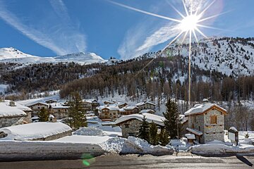 The sun shines brightly over a snowy mountain village