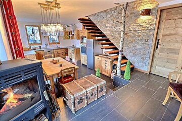 A living room with a wooden table and chairs and a fireplace
