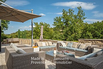 A patio with a lot of furniture and an umbrella made in provence by janssens immobilier