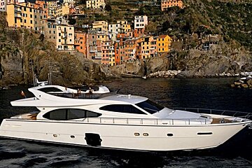 A large white yacht is in the water near a small town