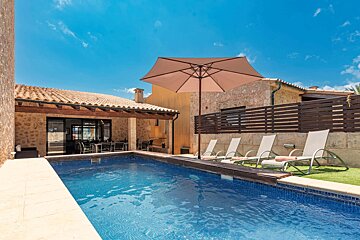 A large swimming pool surrounded by chairs and an umbrella