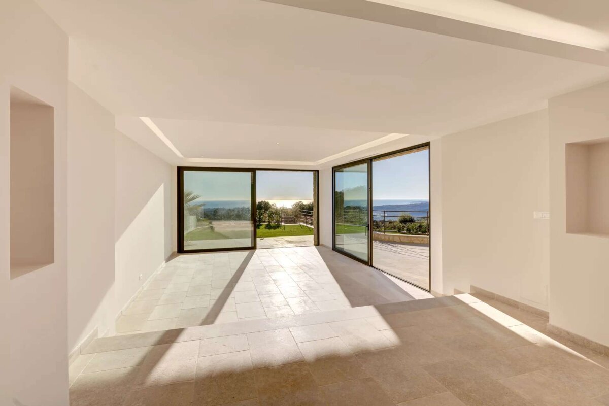 An empty room with sliding glass doors and a view of the ocean