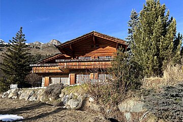 A large wooden house with a mountain in the background