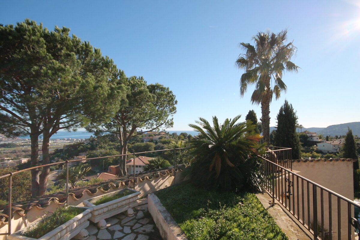 A view of the ocean from a balcony with palm trees