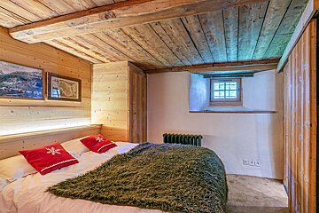 A bed with a green blanket and red pillows with snowflakes on them