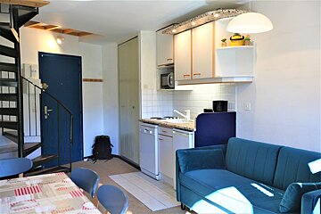 A kitchen with a blue couch and a spiral staircase