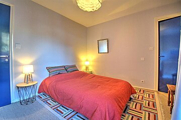 A bedroom with a red bed and a blue door
