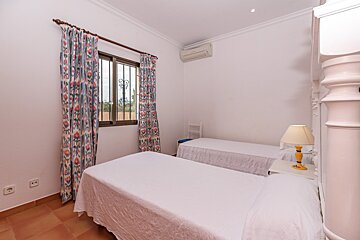 A bedroom with two beds and a lamp