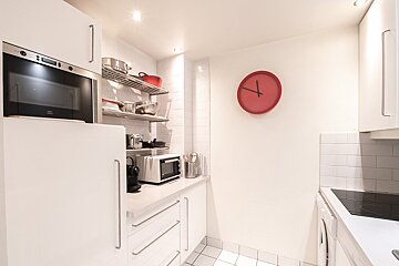 A kitchen with a red clock on the wall that says 4:20