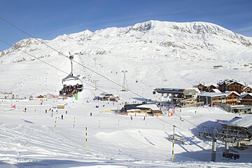 A ski lift is going up a snow covered slope