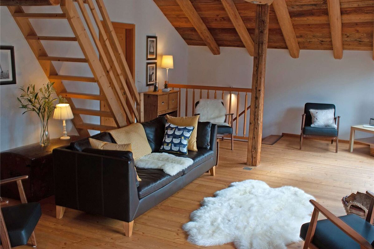 A living room with a couch and chairs and a staircase