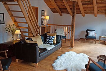 A living room with a couch and chairs and a staircase