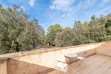 A balcony with a table and chairs and trees in the background
